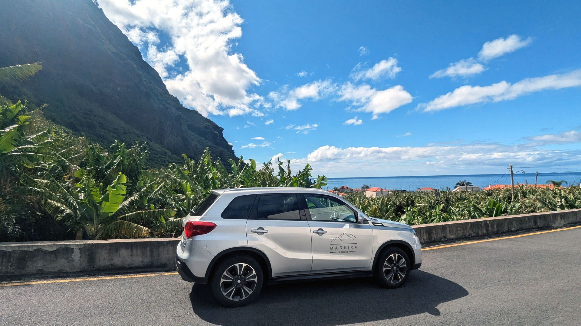 Suzuki Vitara Hybrid in Madalena do Mar on a sunny day, with banana terraces rising on the mountain and the ocean visible in the distance